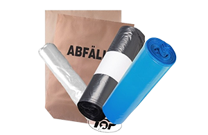 Eine braune Tüte mit dem Wort Abfall daneben liegen drei Rollen Müllbeutel in grau, schwarz und blau.